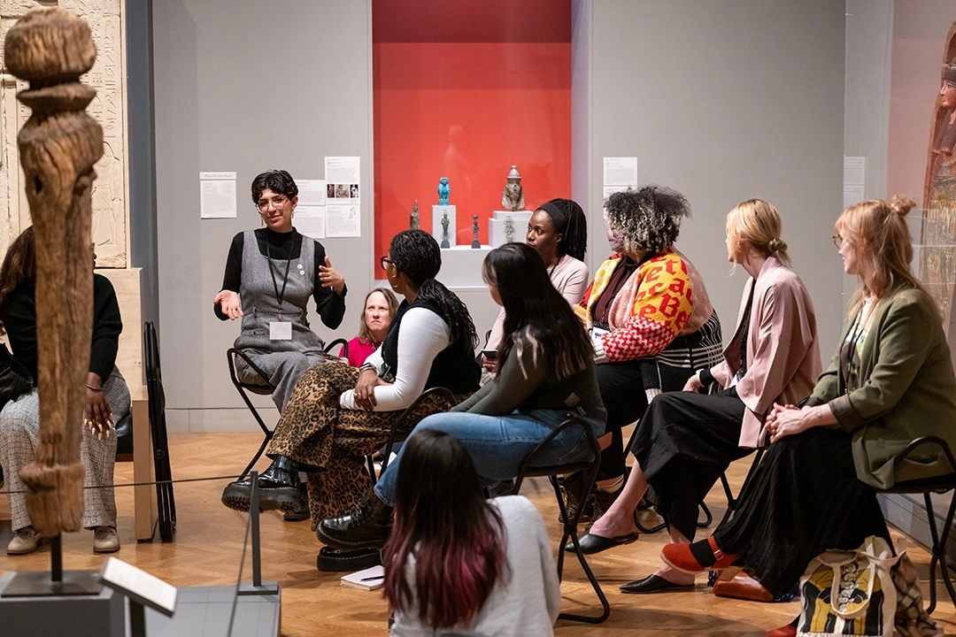 group of people seated in chairs at a museum observing a sculpture
