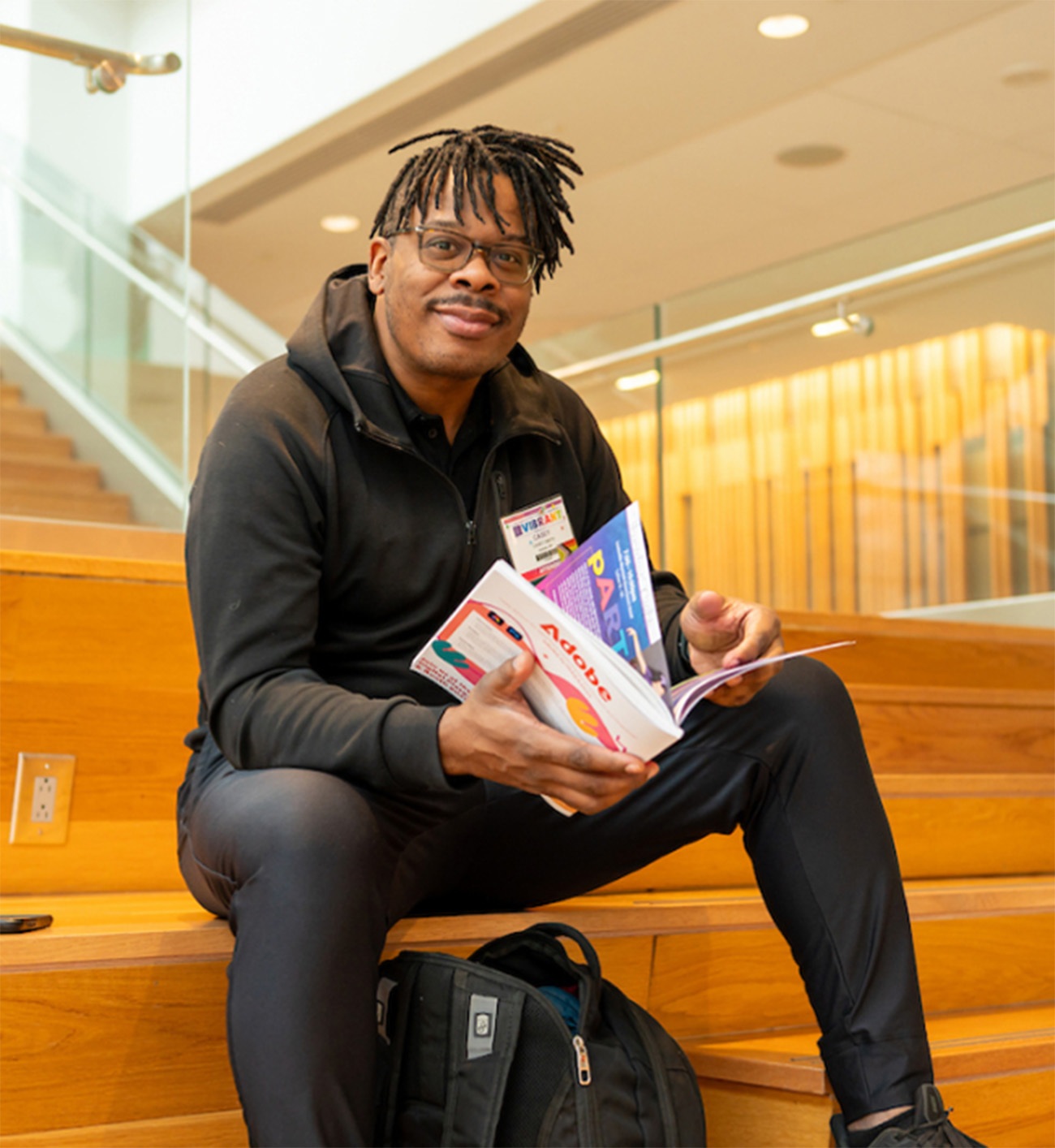 A person sitting on wooden stairs and holding an NAEA Convention program